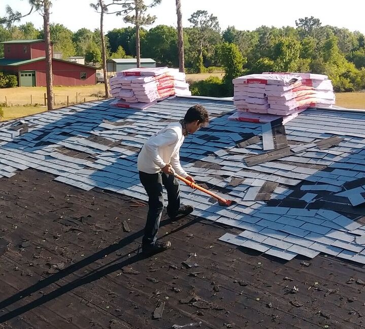 Roofer removing roof shingles for a roof replacement in Kissimmee, Florida